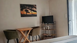 Ein Hotelzimmer mit einem Bett, einem Schreibtisch mit Stuhl, einem Bild an der Wand und einem Fenster mit Vorhängen.