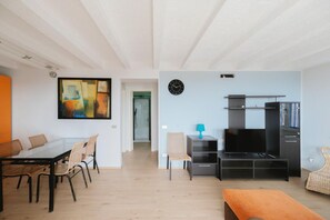 Ein modernes Wohnzimmer mit einem Glastisch, Stühlen, einem Fernseher und einem großen abstrakten Gemälde.