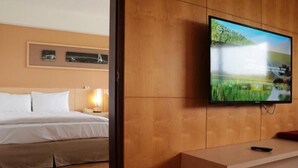 Ein Hotelzimmer mit Bett, Wandfernseher und Holzpaneel-Design.