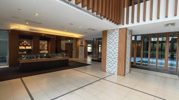 Eine geräumige Lobby mit Empfangstresen, einer Treppe und großen Fenstern.