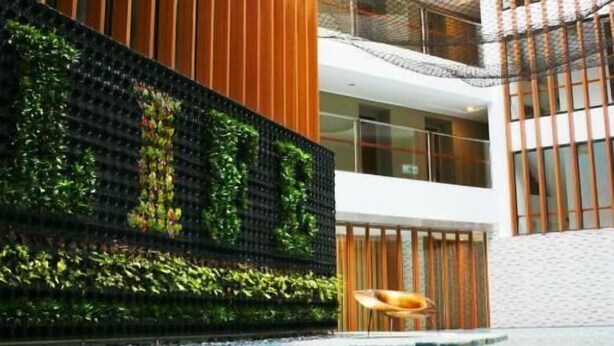 Un bâtiment moderne doté d’un jardin vertical, d’une piscine et d’un espace détente.