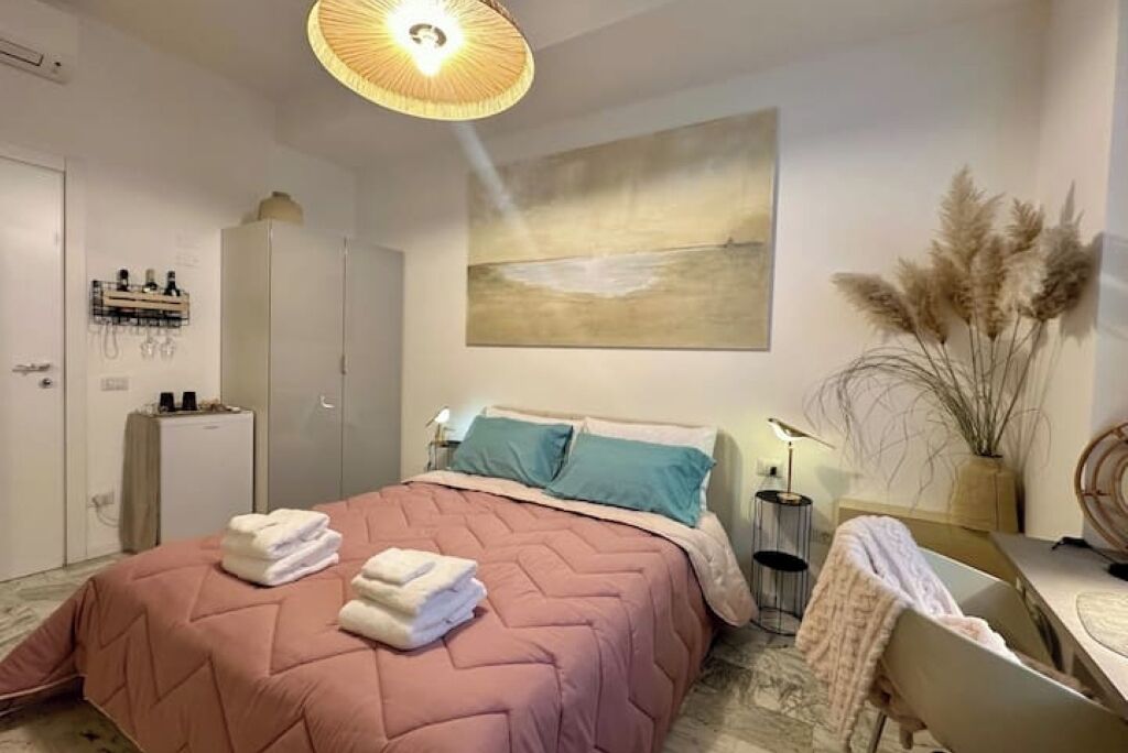 Une chambre à coucher avec un lit, une table de chevet, une lampe et un tableau au mur.