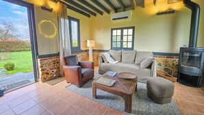 A cozy living room with a stone wall, a sofa, a leather chair, a wooden coffee table, and a fireplace.