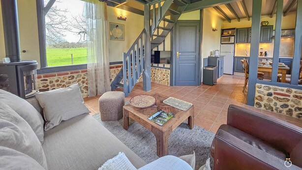 A cozy living room with a sofa, a coffee table, and a staircase leading to a kitchen.