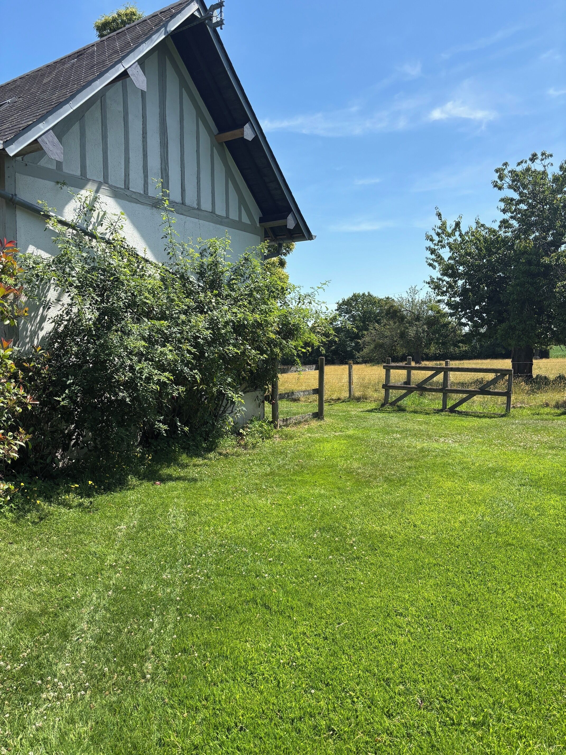A house with a sloped roof, a fenced yard, and a clear blue sky.