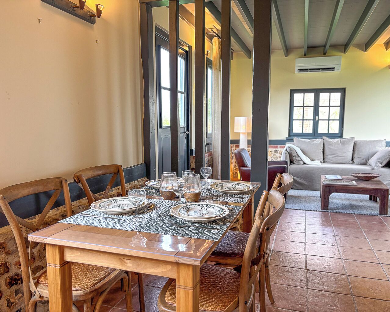 Un coin repas avec une table en bois dressée pour six personnes, entourée de chaises en bois.