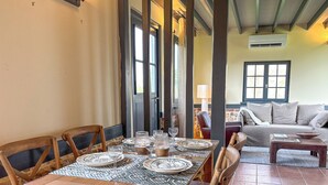 A dining area with a wooden table set for six, surrounded by wooden chairs.