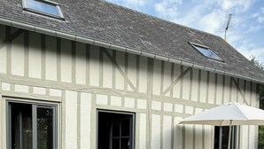A Tudor-style house with a patio, a bench, a table with chairs, and a garden.