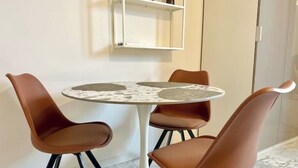 Una mesa redonda con una superficie que imita el mármol, rodeada por cuatro sillas marrones con patas negras.