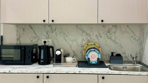 Una cocina equipada con microondas, cafetera y escurreplatos.