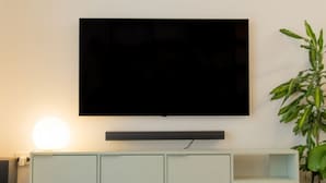 A flat-screen TV mounted on a wall above a light-colored cabinet with a shelf below. - Sonnino 17 Luxury Apartment (Cagliari)