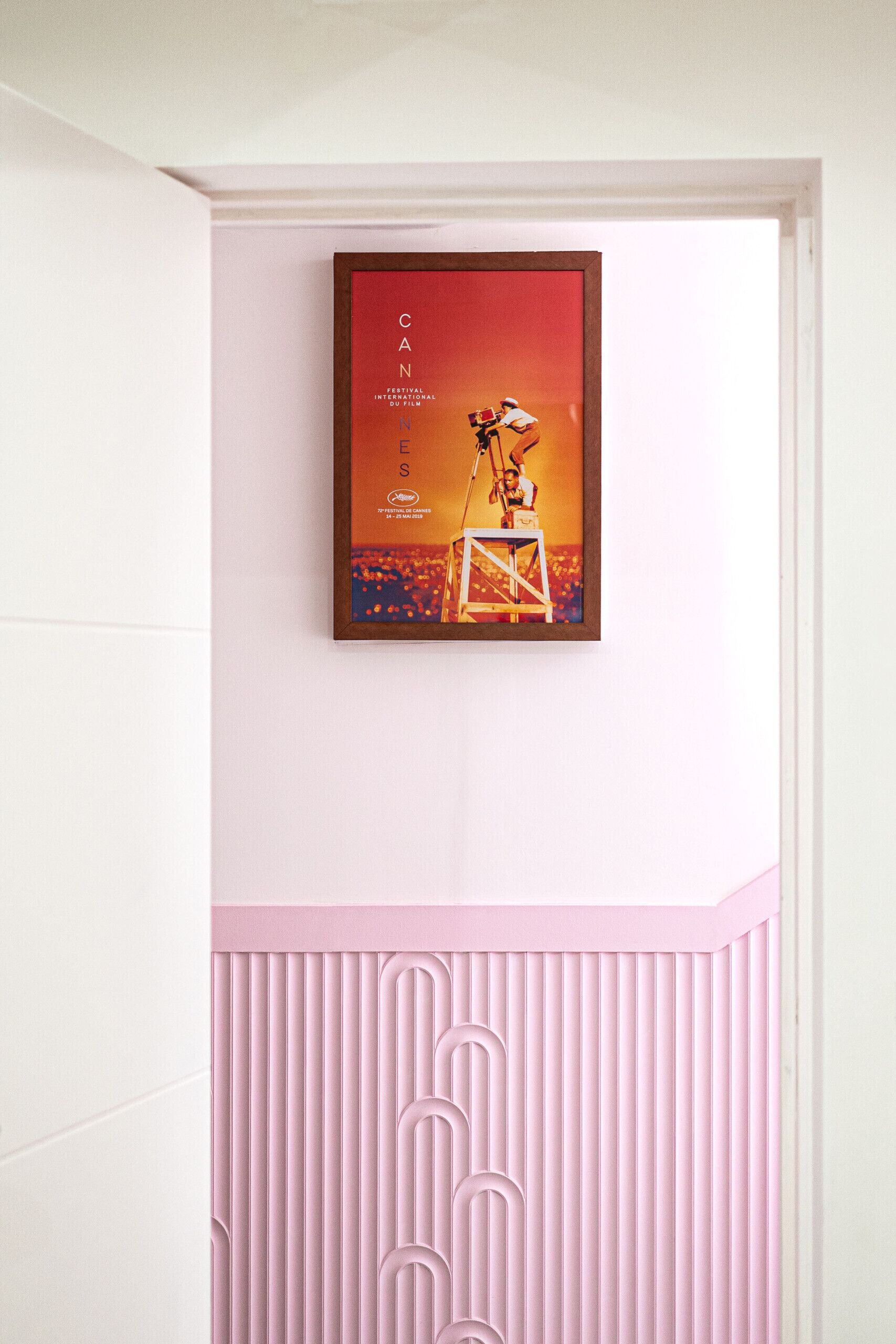 Ein gerahmtes Bild an der Wand, darunter ein pink-weißes Design.