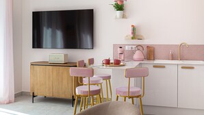 Une cuisine moderne équipée d’un téléviseur à écran plat, de chaises roses et d’un coin café.