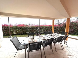 An outdoor patio with a table set for dining, surrounded by chairs, and a view of a garden with pink flowers. - Beautiful  villa with WIFI, A/C, TV, terrace, pets allowed and panoramic view, close to Viareggio (Corsanico-bargecchia)