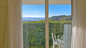 Habitació amb vista a un paisatge costaner, una finestra amb cortines i una cadira a l'exterior.
