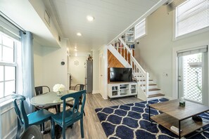 A modern living room with a dining area, a staircase, and a TV on a wooden stand. - Twin Palms on Julia - Heart Of It All - 2BD/2Bath - May - August 10% off! (Key West)
