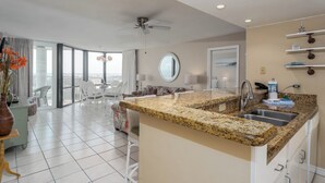 A modern kitchen with granite countertops, a built-in sink, and a ceiling fan. - Saida Royale 145 - Premier Location with Breathtaking Ocean Views. The Only Thing Missing is You! (South Padre Island)
