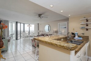 A modern kitchen with granite countertops, a built-in sink, and a ceiling fan. - Saida Royale 145 - Premier Location with Breathtaking Ocean Views. The Only Thing Missing is You! (South Padre Island)