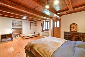 A room with a bed, a wooden dresser, a bookshelf, and a window.