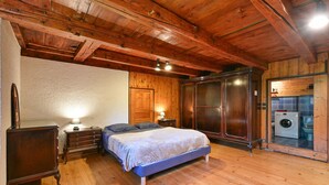 Ein Schlafzimmer mit Holzboden, einem Bett, einem Schminktisch, einem Nachttisch, einer Lampe und einer Waschmaschine.