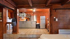 Ein Holzblockhaus im Inneren, mit Küche, einem Bett und einer Treppe.