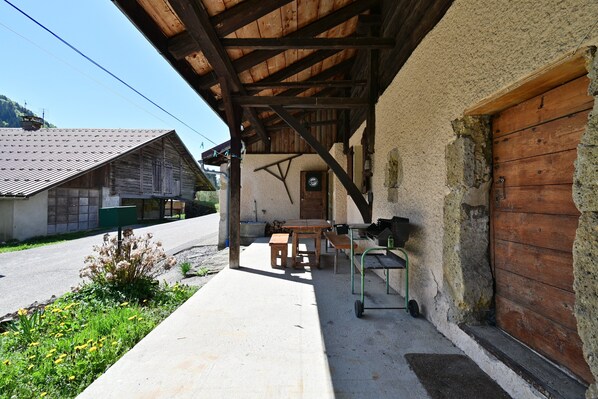 A rustic building with a wooden porch, a green cart, and a door.