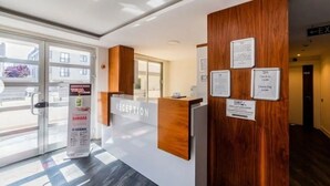 A reception area with a wooden reception desk, glass doors, and a view of the outside.