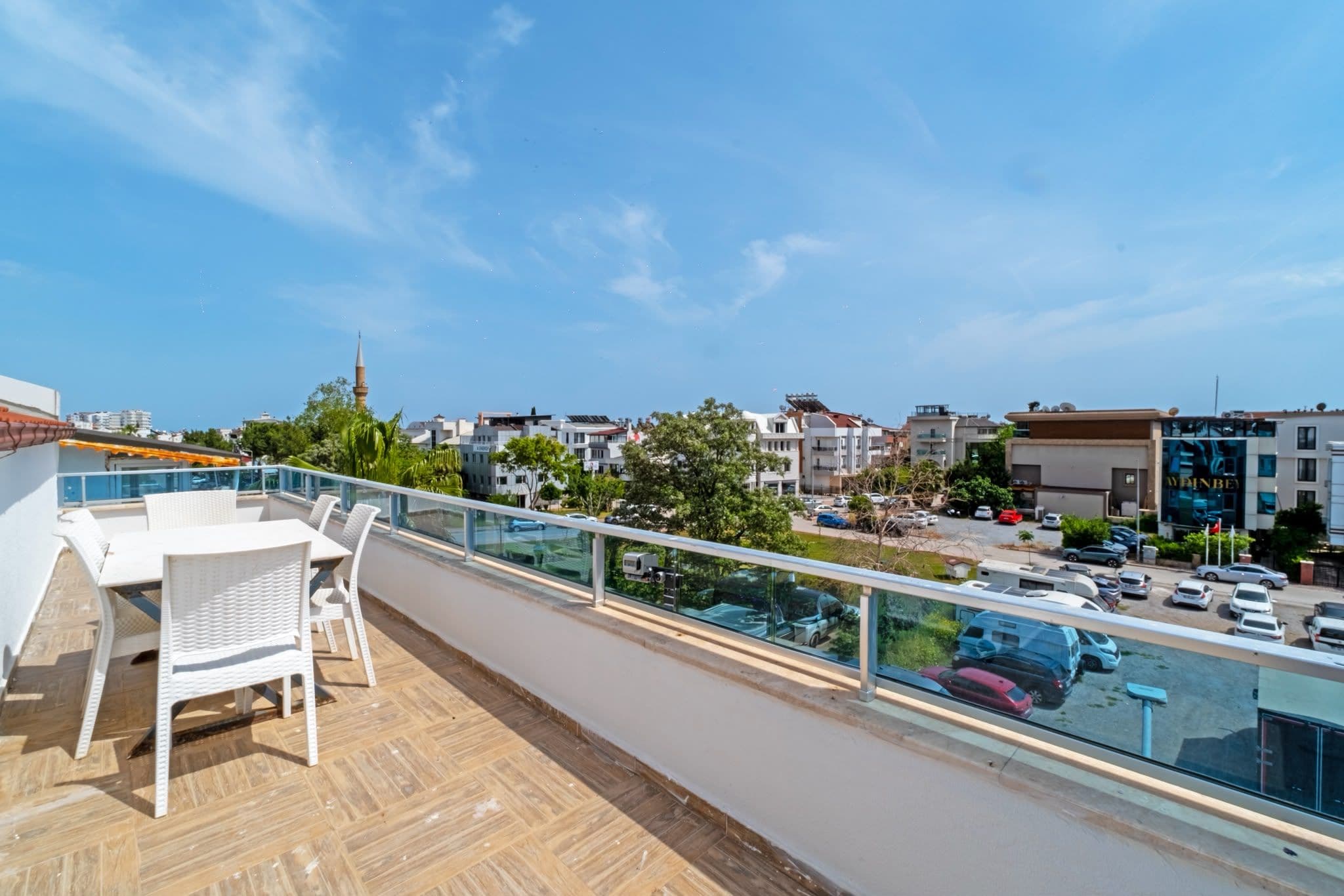 Ein Balkon mit Blick auf eine Stadtlandschaft, darunter Gebäude und parkende Autos.