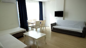 A hotel room with a bed, a sofa, a small table, and a TV mounted on the wall. - Hey Lara Hotel (Antalya)