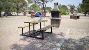 A picnic area with a brick barbecue grill and wooden picnic tables. - Hey Lara Hotel (Antalya)