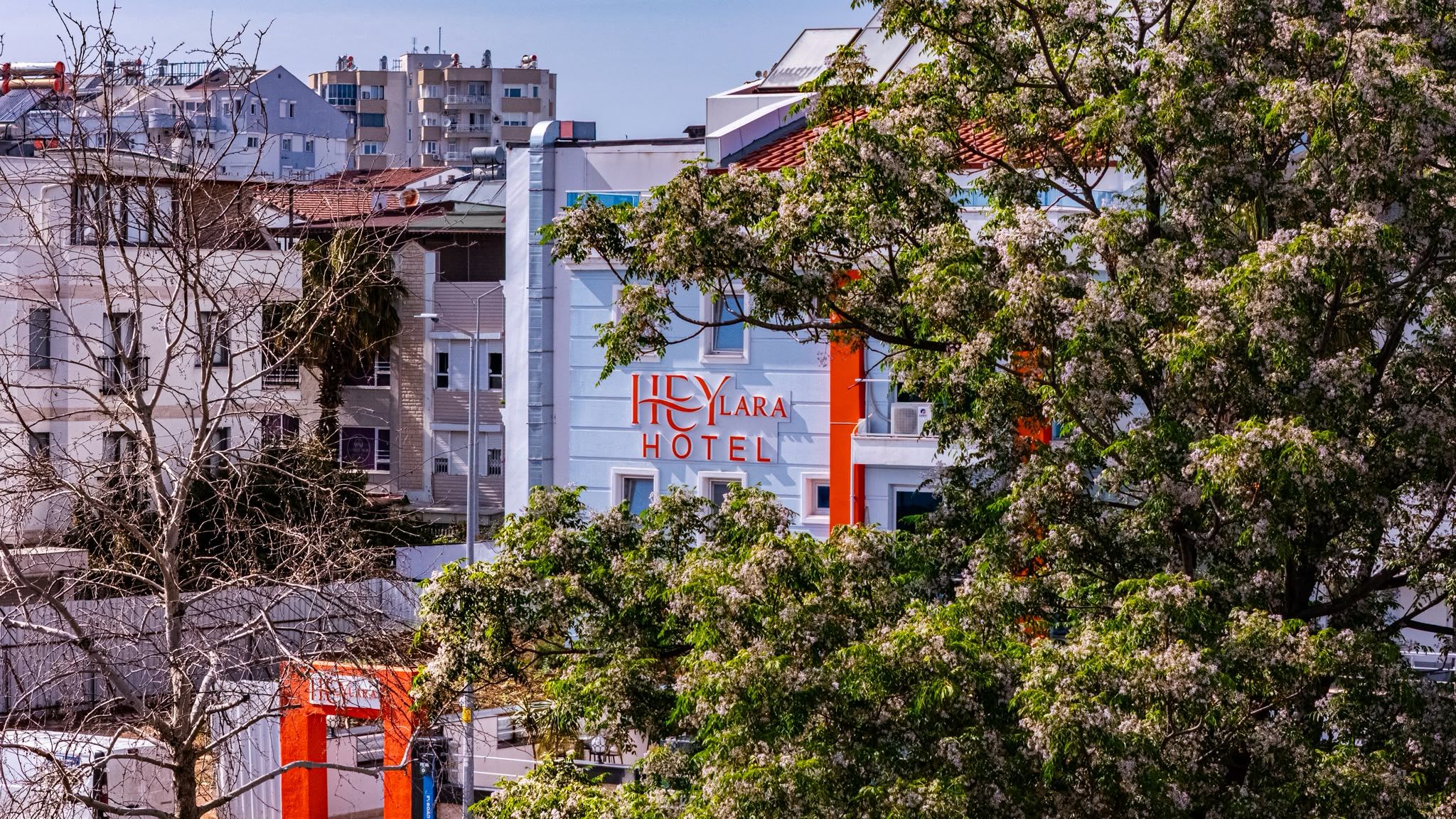 Edificio de hotel con un letrero que dice 'HeyLara Hotel' y una puerta de entrada roja.