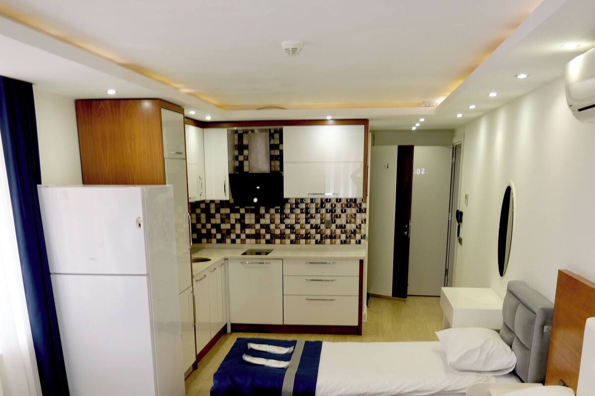 A hotel room with two beds, a kitchenette, a bathroom, and a small sitting area.