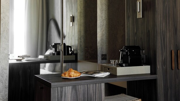Une salle de bain moderne avec un grand miroir, des meubles en bois foncé, un lavabo et un porte-serviettes.