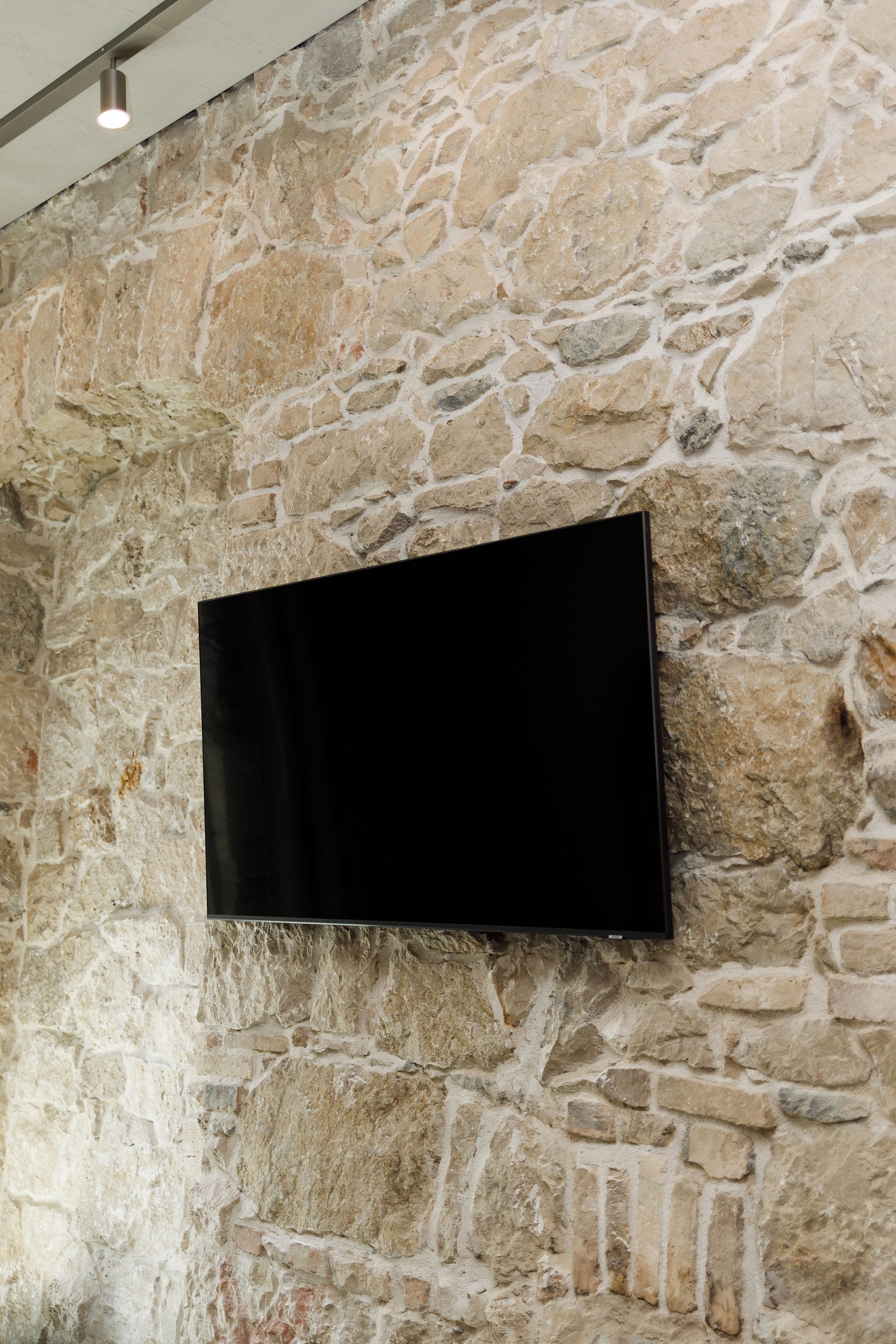 Ein Flachbildfernseher an einer Steinwand befestigt.