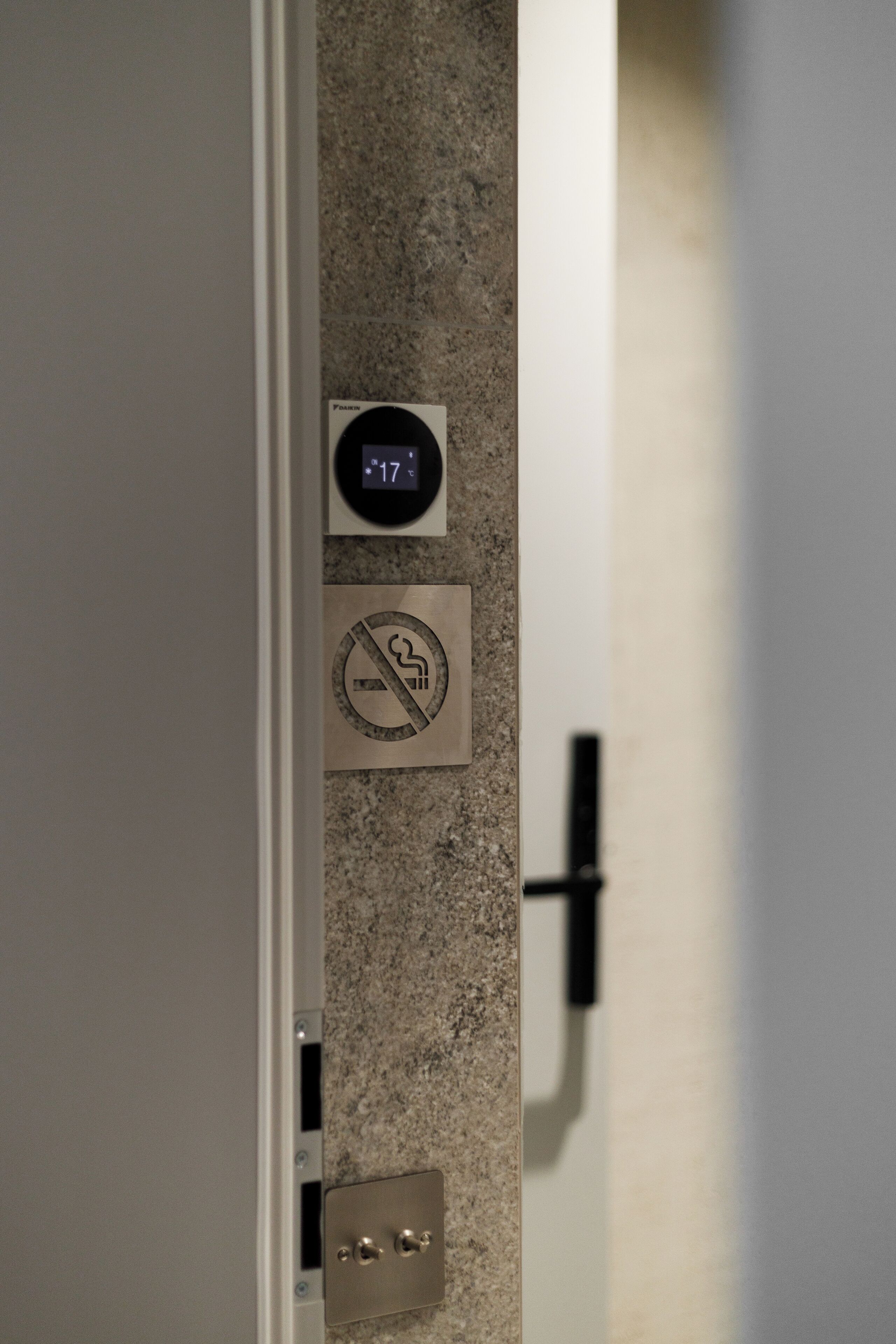 A wall-mounted digital display with a temperature reading of 17 degrees, a no-smoking sign, and a door handle.