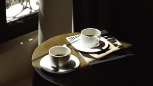 Une table avec une tasse de café et un menu, placée près d’une fenêtre donnant sur un balcon.