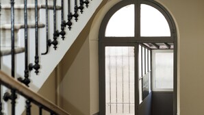 Un escalier avec des balustres noires menant à un palier doté d’une grande fenêtre en arc de cercle.