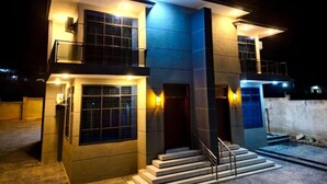 A modern two-story building with a staircase leading to the entrance, large windows, and exterior lighting. - GFG Luxury Apartment (Mwanza)