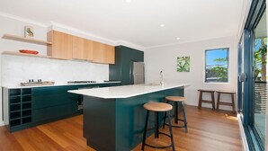 A modern kitchen with a central island, wooden cabinets, and a view of the outdoors.