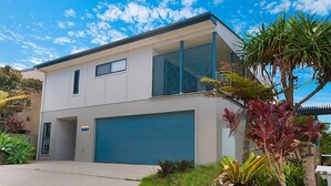 A modern two-story house with a garage, large windows, and a balcony.