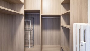 Un dressing avec des étagères en bois, un étendoir métallique et un radiateur.