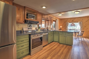 A kitchen with wooden cabinets, a stainless steel refrigerator, a microwave, and an oven.
