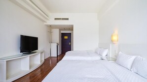 A hotel room with a TV on a glass stand, two beds with white bedding, a bedside table with a lamp, and a door leading to another room. - Island Heart Sun Moon Lake Hotel (Yuchi)