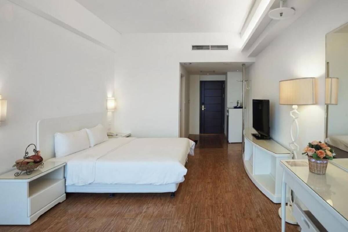 A hotel room with a bed, bedside tables, a TV, and a mirror.