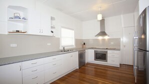 A modern kitchen with white cabinetry, a stainless steel refrigerator, an oven, and a dishwasher. - My Blue Heaven Dog Friendly (Lennox Head)