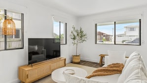 Una sala de estar moderna con televisor, sofá y una planta en maceta.