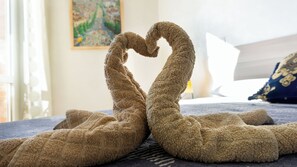 Un lit recouvert d’une couvre-lit à motifs bleus et blancs, un coussin décoratif aux motifs bleus et dorés, et un tableau accroché au mur.