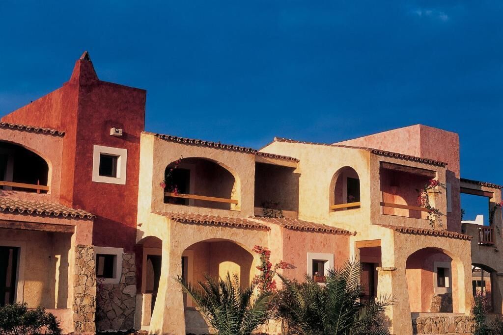 A multi-story building with arched windows and balconies, featuring a mix of stone and stucco exteriors.