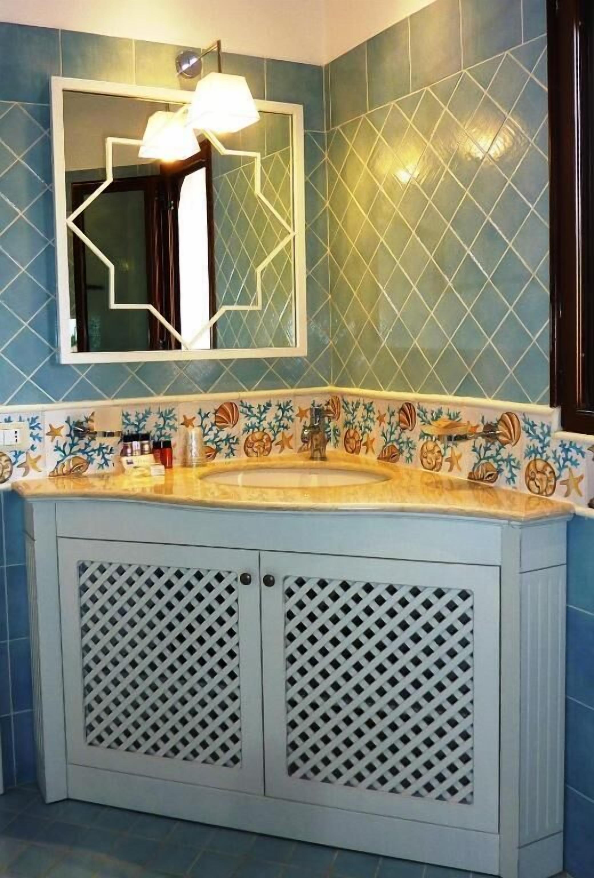 A bathroom with a sink, mirror, and decorative tiles.