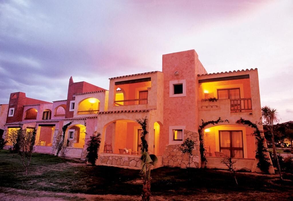 A multi-story building with balconies, arched doorways, and a stone facade.